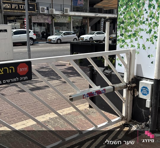 שער חשמלי ברחוב עם שלט אזהרה